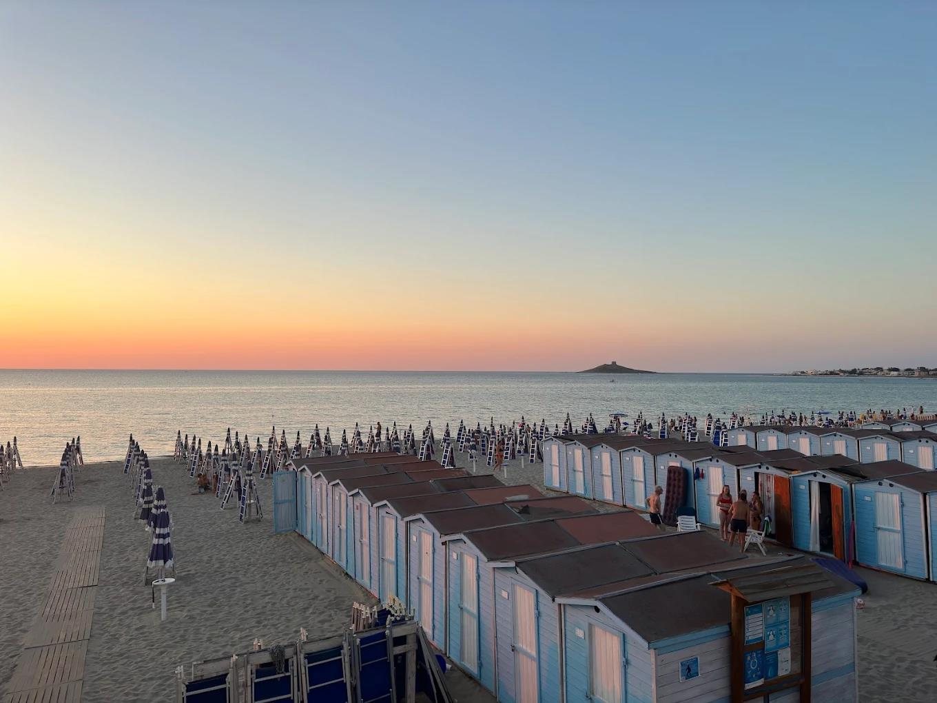 Beach cabins and parasols at sunset in Isola delle Femmine