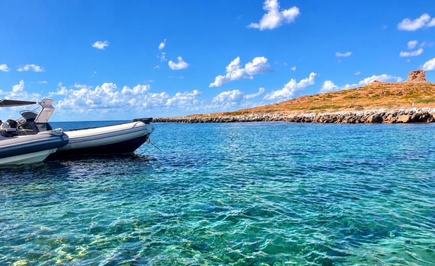 Boat in turquoise water beside a rocky headland