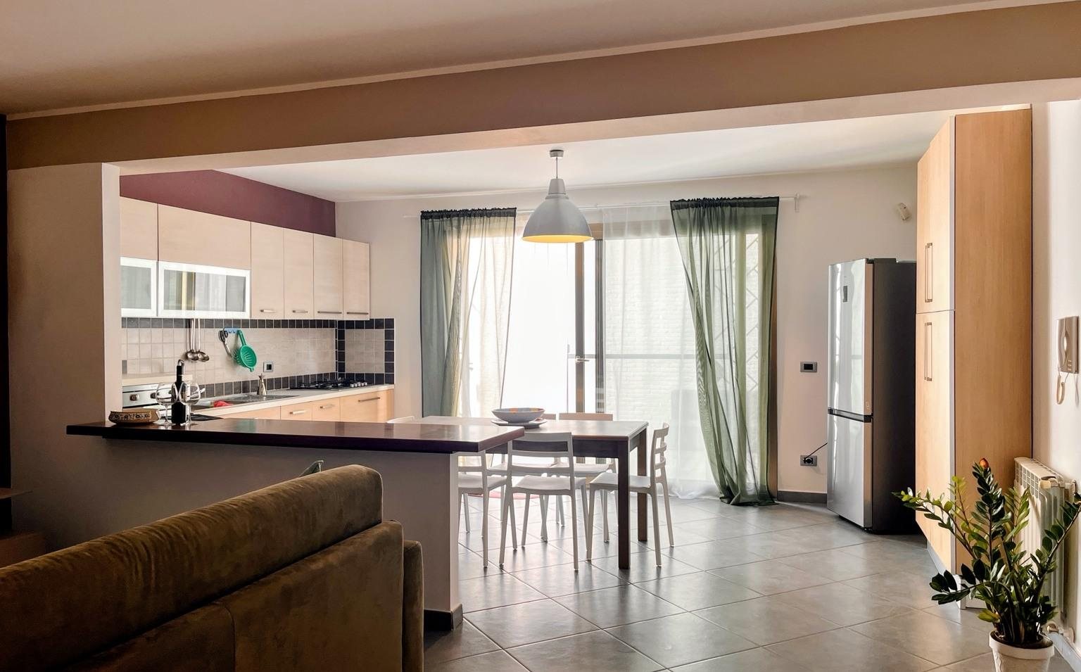 Open-plan living area with kitchen and dining table at Isola Dream